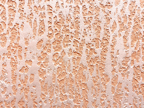 Embossed pastel yellow-pink color plaster wall texture. Copy space. Abstract background for design close-up. Painted cement facade.