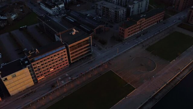 Aerial of cars riving on the road alongside the buildings during the golden sunset