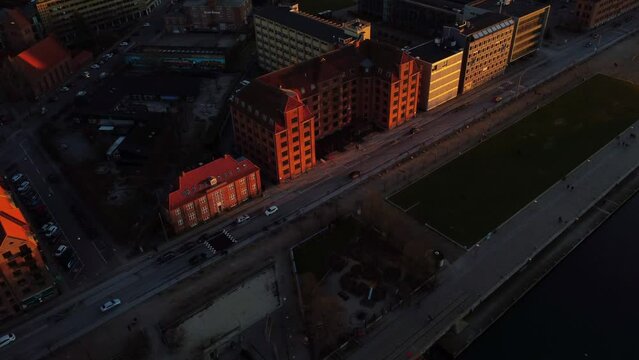 Aerial of cars riving on the road alongside the buildings during the golden sunset