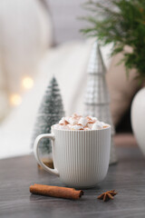 cup of cacao with marshmellows, christmas tree on coffee table on white pillow background.