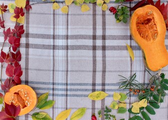 frame with flowers, checkered beige autumn background with edible cut pumpkin and crimson yellow...