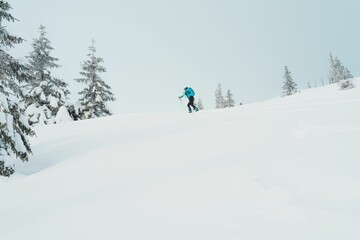 Fototapeta na wymiar Caucasian man wearing a blue jacket riding down a snowy mountain slope
