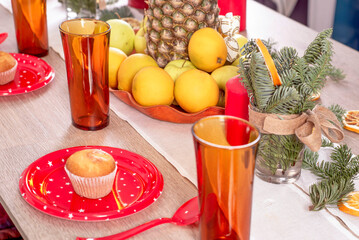 Christmas holiday table decorated with candles, Christmas tree branches, dried oranges, sweets and fruits,selective focus.Cozy house decorated for the holiday with handmade items.Christmas decoration