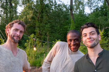 In the vibrant backdrop of an outdoor party, three male friends from different ethnicities come together, epitomizing the strength of friendship and the beauty of diversity. Their genuine smiles, side