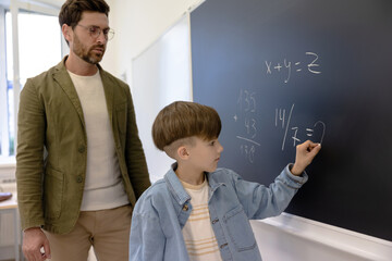 The boy answering at the maths lesson and writing on the board