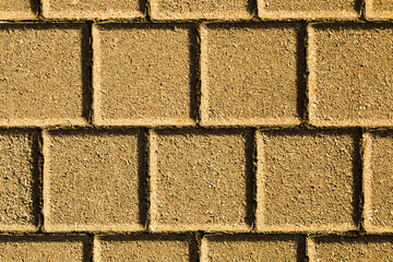 Cobblestone pavement. Square shape bricks. Gray walking path. Paved texture. Street tile background. Blank empty copy space blocks. Yellow color urban texture.