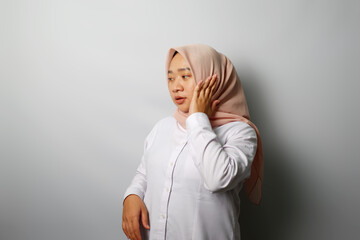 A portrait of young smiling Muslim woman wearing a pink hijab over white background studio.