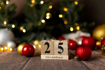 Old vintage wooden calendar for the date of Christmas December 25 against the background of New Year's lights of garlands of bokeh light bulbs - obrazy, fototapety, plakaty