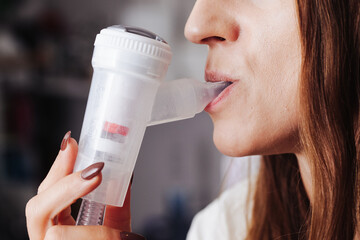 Nebulizer device in mouth. Woman with inhaler in her mouth background. Breathing saline through nebulization. Mouth inserted nebulizer. Lung and throat treatment. - obrazy, fototapety, plakaty