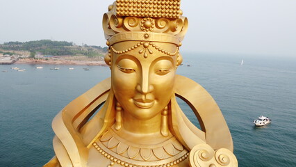A stone Buddha gazes over Qingdao's azure waters, blending spirituality with the maritime calm.