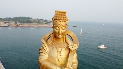 A stone Buddha gazes over Qingdao's azure waters, blending spirituality with the maritime calm.