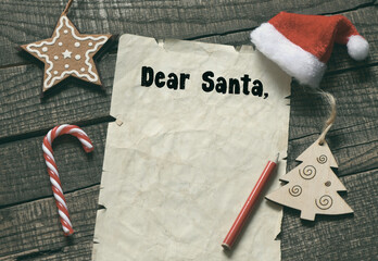 Lettering wish card written to Dear Santa text by kid on wooden desk with Christmas.
