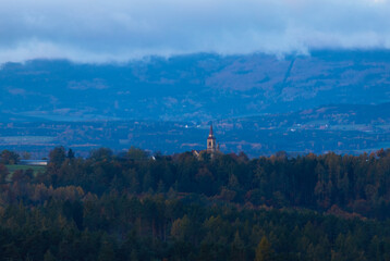 Catholic church in small Czech vilage Hosin in autumn landscape at blue hour