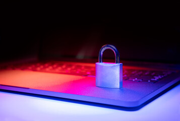 Closeup of a padlock on a laptop illuminated with blue and red light. Phishing, cybersecurity danger or ransomware attack. Encrypted privacy in email.