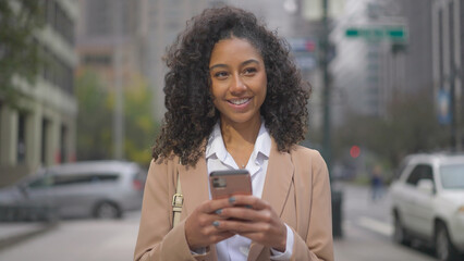Young black business woman using smart phone on city street - Powered by Adobe