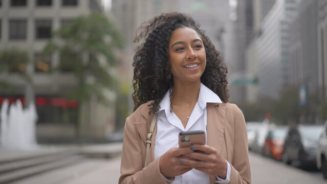 Young black business woman using smart phone on city street - Powered by Adobe