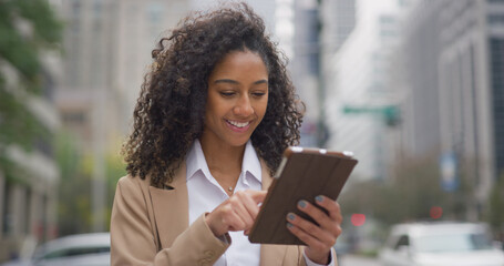 Young black business woman using tablet computer on city street