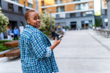 A young casually dressed girl holds the phone in her hand while waiting for her friends to go and socialize