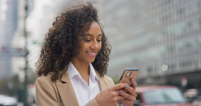 Young black business woman using smart phone on city street