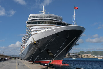 Classic british luxury ocean liner cruiseship cruise ship in port with detail view of steel hull, bow, superstructure and bridge in black, white and red color paint