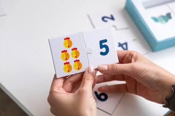 Math puzzle for young children. Two cards in a woman's hand.