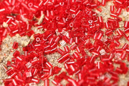 Landart, close-up of scattered red beads on a rock
