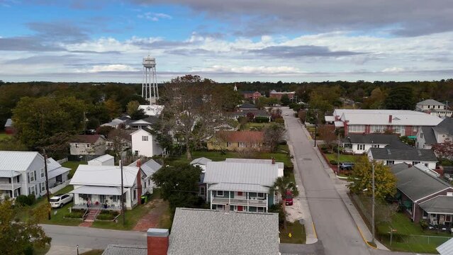 A slowly rising forward aerial establishing shot view of the quaint little town of Swansboro, North Carolina. Water tower and church steeple in the distance.  	