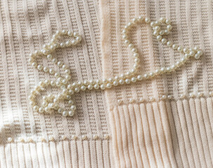 Concept shot of the pearl necklace on the woolen scarf. Jewelry