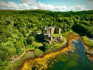 Majestic castle stands tall overlooking a tranquil body of water in Dunvegan, Scotland