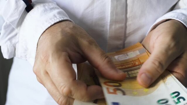 A man counts 50 euro bills, close-up of his hands. Business and finance concept.