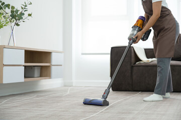 Woman cleaning house using vacuum cleaner.
