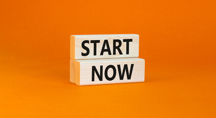 Start now symbol. Concept words Start now on beautiful wooden block. Beautiful orange table orange...