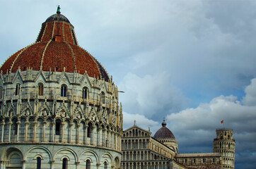 Stunning landscape view of Pisa Baptistery, Pisa Cathedral and Leaning Tower of Pisa against stormy sky and gloomy clouds. Notable landmark of Pisa, Italy. UNESCO World Heritage Site