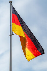 The national flag of Germany waving in the blue sky