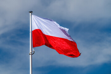 The national flag of Poland waving in the blue sky