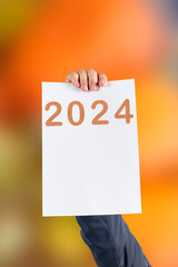 2024, Man holding cardboard with number 2024 on orange background. Happy New Year