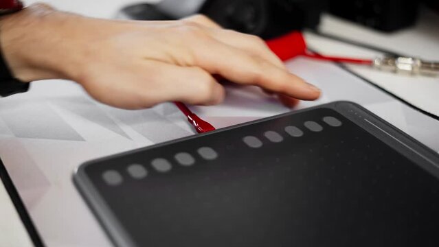A man connects a graphics tablet via the Type interface With a bright red cable. Close-up of the hands.