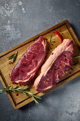 Vertical overhead shot, showcasing raw striploin and New York steaks meticulously placed on a...