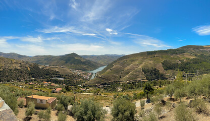 majestatyczne chmury nad wzgórzami porośniętymi winoroślą a w dole płynąca rzeka Duoro. Portugalia