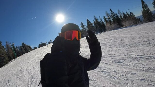 This scene showcases a snowboarder enjoying a sunny day on the slopes, with fresh snow underfoot and a backdrop of trees and a clear sky.