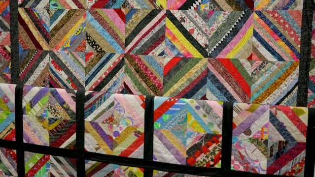This video shows a close up view of a detailed and colorful hand made quilt.