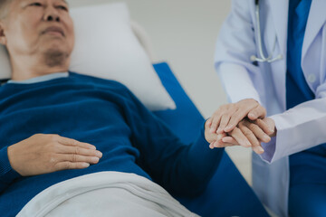 Obraz premium Beautiful Asian female doctor in white top talking with senior patient at bedside in hospital or clinic ward