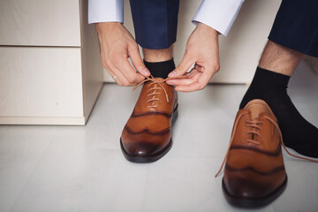 Male businessman puts on stylish shoes. man getting ready for work,groom morning before wedding...