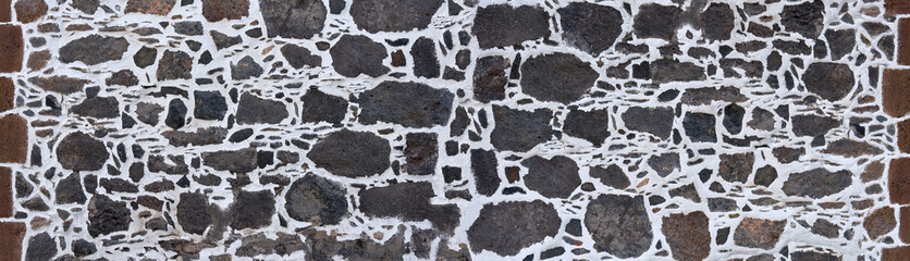 Kanarische Mauer aus grauem vulkanischem Gestein in weißem Verputz, am Rand eingefasst mit braunen Steinen - obrazy, fototapety, plakaty