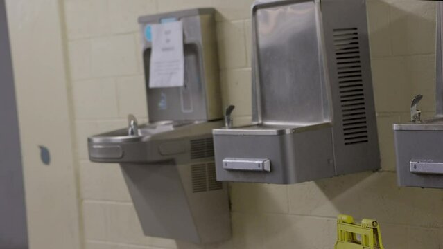 This panning video shows a row of old water fountains.