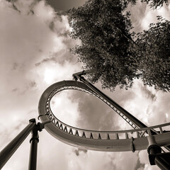 Rollercoaster loop detail, with sky and tree in the background. POV looking up, black & white...