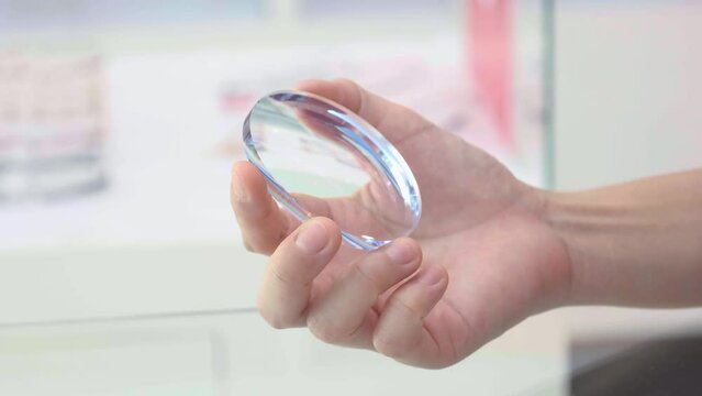 close up of hand holding glasses lens 