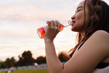 Portrait of beautiful girl drinking lemonade while standing in park - obrazy, fototapety, plakaty