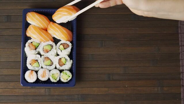 Top-Down Sushi Platter. Chopsticks Selecting Sushi Pieces in Aerial View. jump-cut technique.