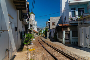 Fototapeta na wymiar Street - railway. A small street in Nha Trang in Vietnam with railway tracks running through the residential sector.
